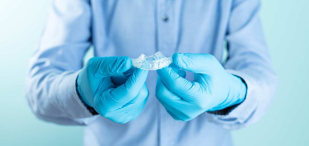 04 A dentist wearing aqua-colored protective gloves holding a dental splint