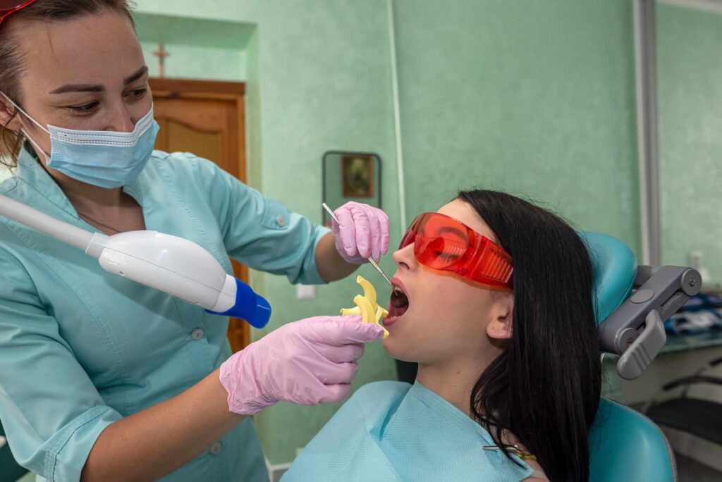 05 A dentist preparing a patient for a type of teeth whitening by photoactivation