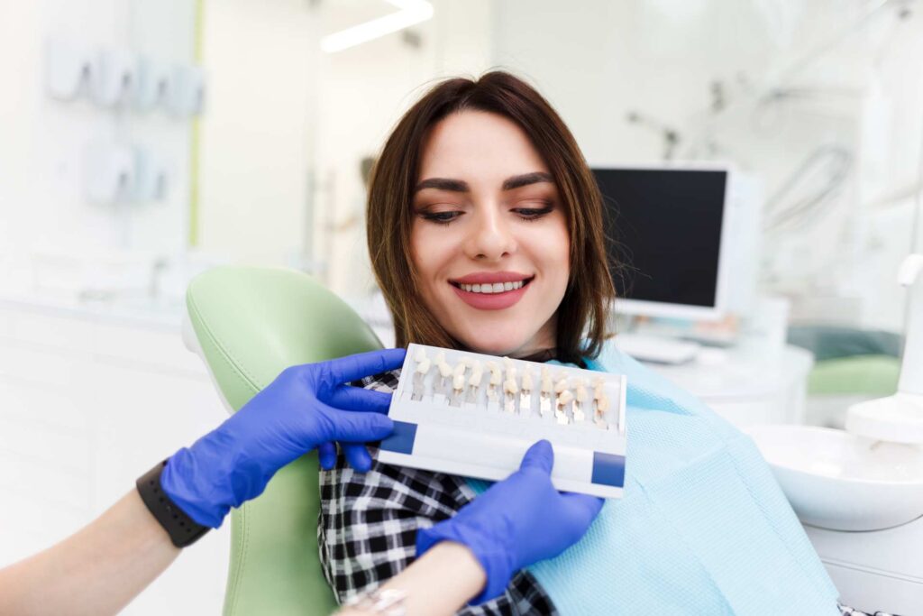 05 Dentist showing young woman dental veneers for her to choose from