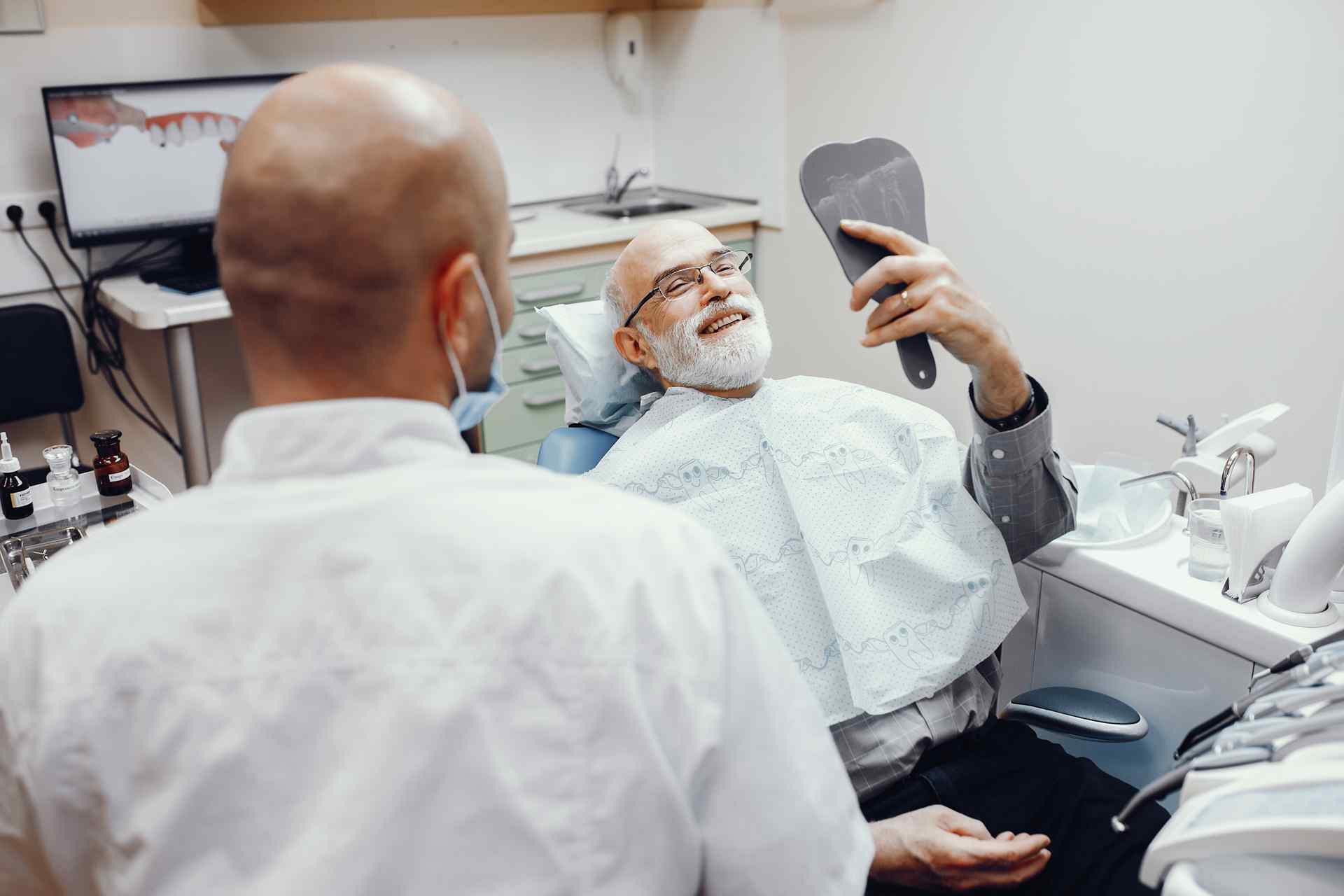 01 Mature, gray-haired man smiling in the dental clinic after a smile makeover