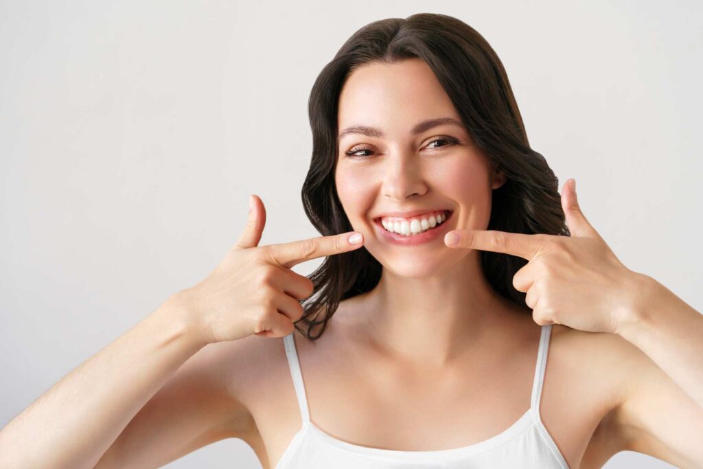 05 A woman signaling her own smile with two index fingers