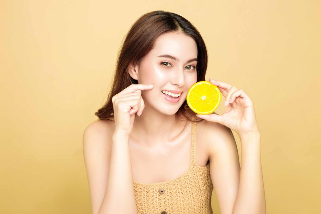 07 Smiling woman pointing out the good effects of citrus fruits and vitamin C on teeth