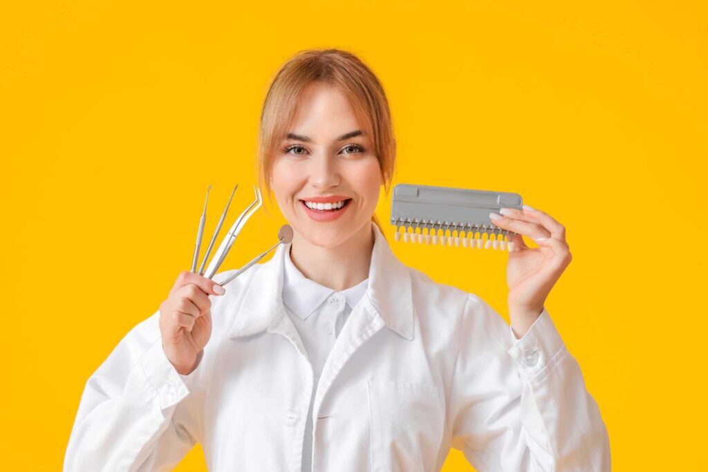 dental specialist holding tools of her profession and a porcelain veneer color chart.
