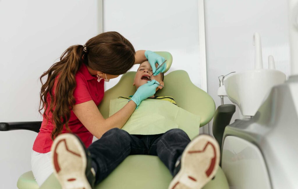 04 Dentist treating a boy in the clinic_Porcelain veneers vs. bonding