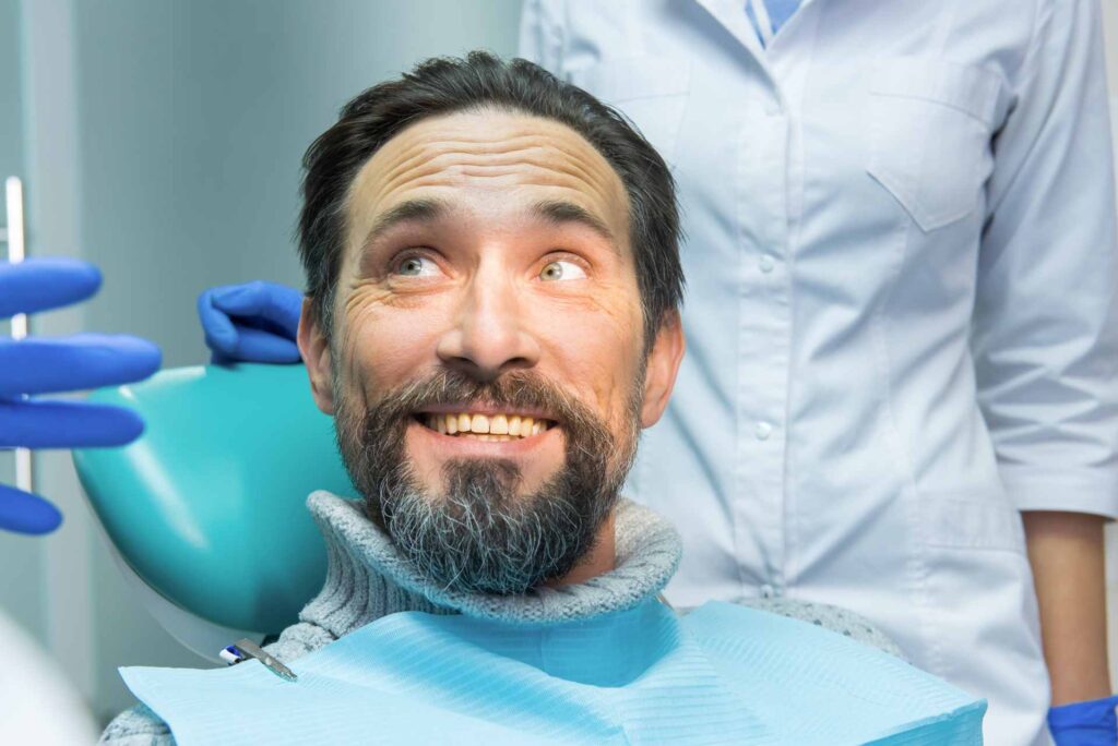 06 Mature man smiling during a consultation with the dentist_Lumineers vs. porcelain veneers