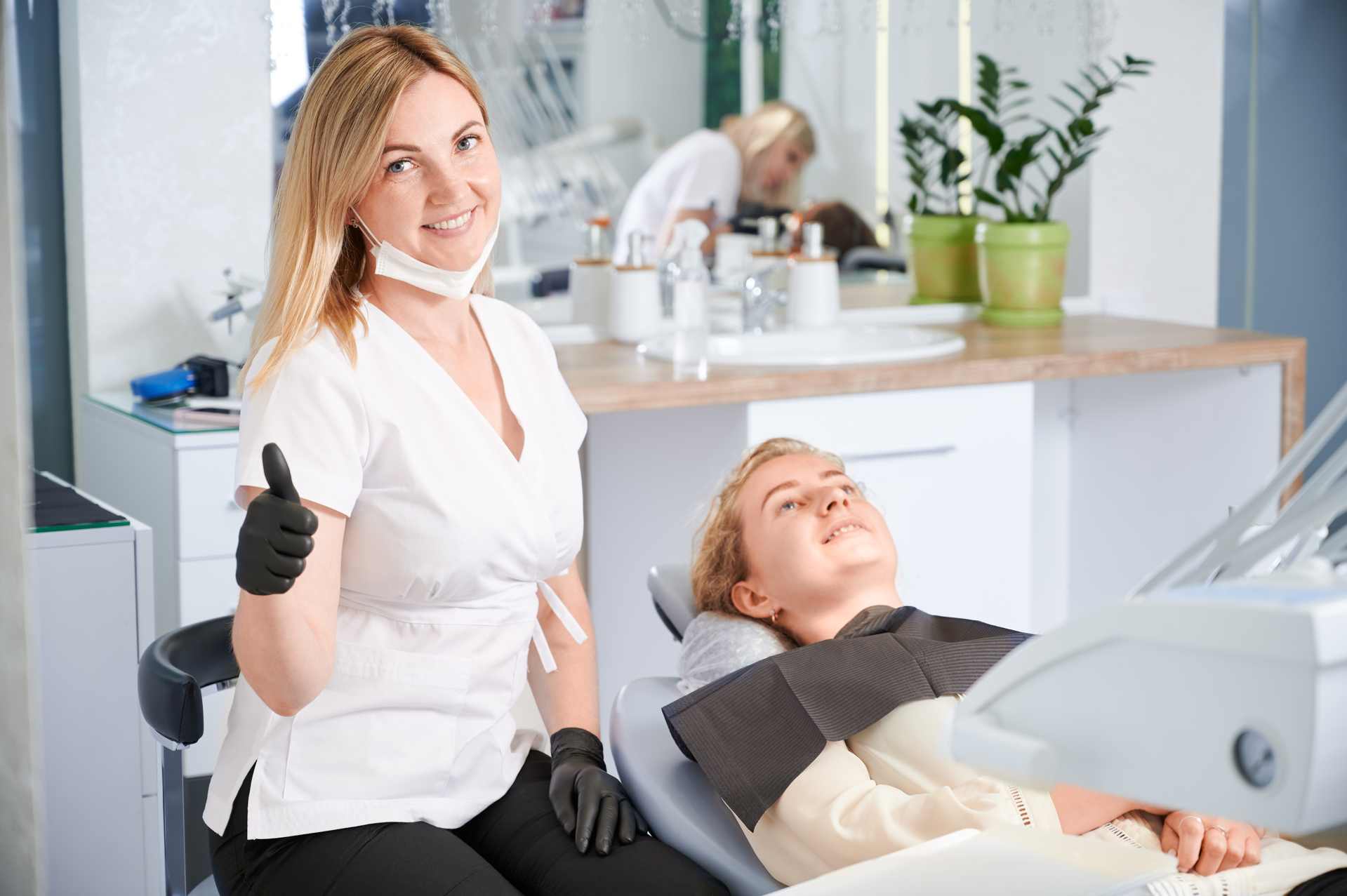 01 Dentist in the clinic making the OK thumbs-up gesture with a patient_Do dental implants hurt