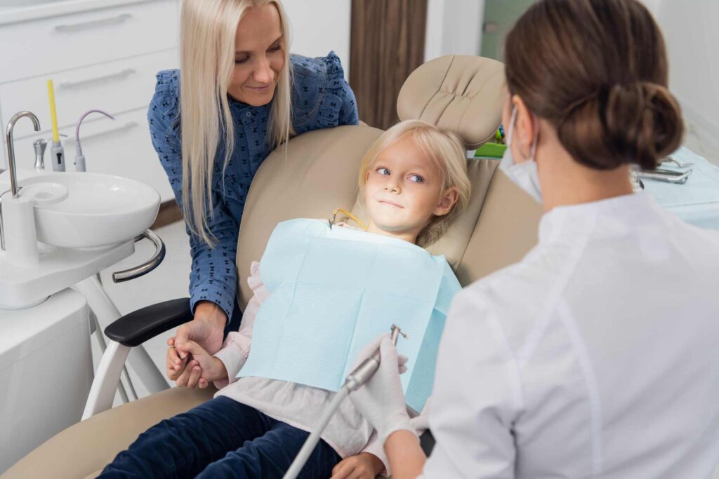 03 A child with her mother receiving dental care at a clinic_Dental insurance in the U.S. covering implants