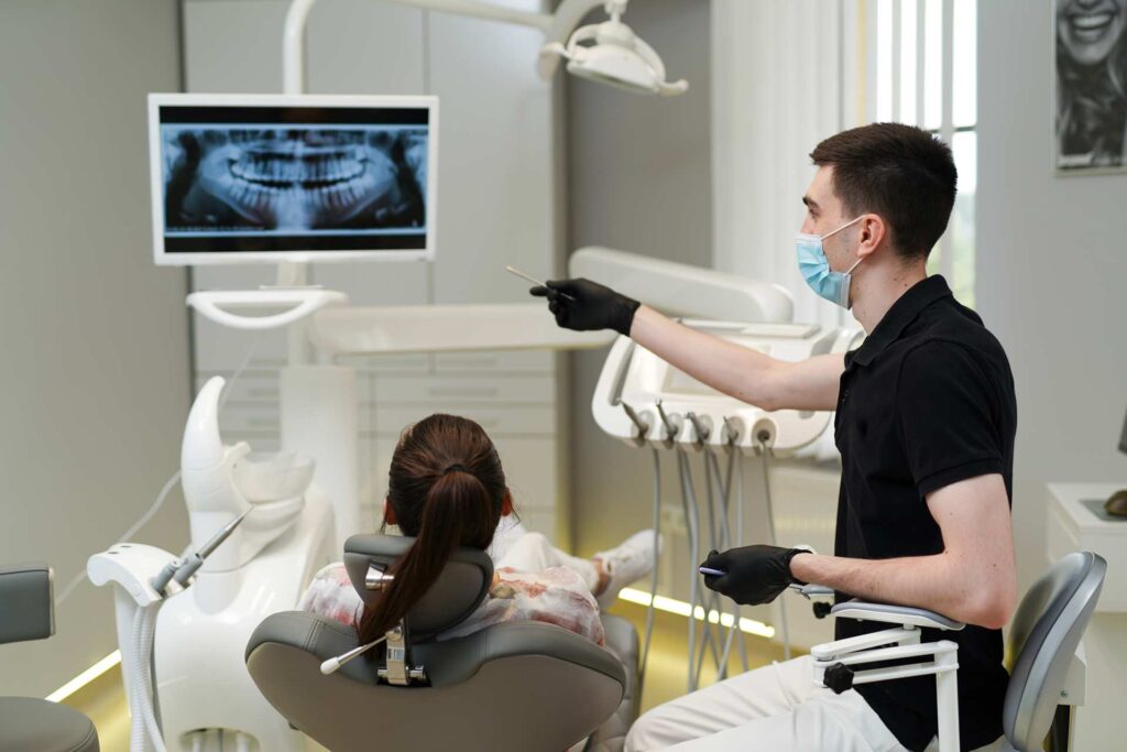 04 Dentist examining an X-ray film with a patient_Dental implants procedure, dental implants in Miami