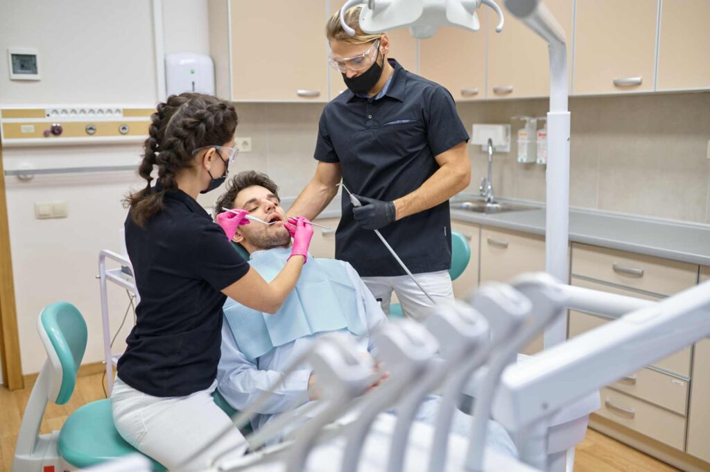 06 Dentist and assistant performing a check-up on a patient in the clinic_Dental insurance in the U.S. covering implants