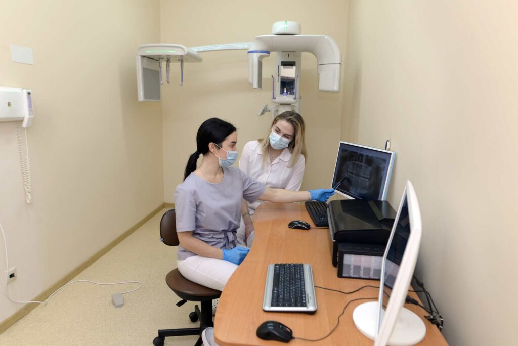 07 Patient with his dentist examining a dental X-ray film_Dental insurance in the USA covering implants