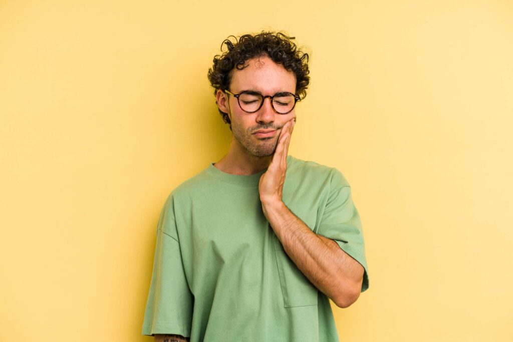 09 A man with glasses on a yellow background experiencing toothache_How soon after dental implants can I eat normally