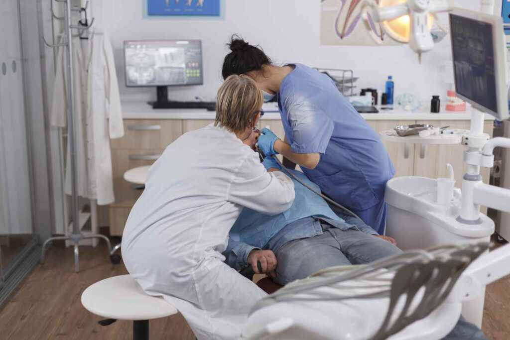 11 Dentist and her assistant attending to a patient in the clinic_Dental insurance in the U.S. covering implants