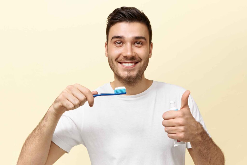 08 Young man brushing his teeth gives a thumbs up and smiles