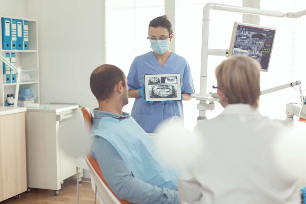 09 Dentist analyzing a dental X-ray with patient and assistant