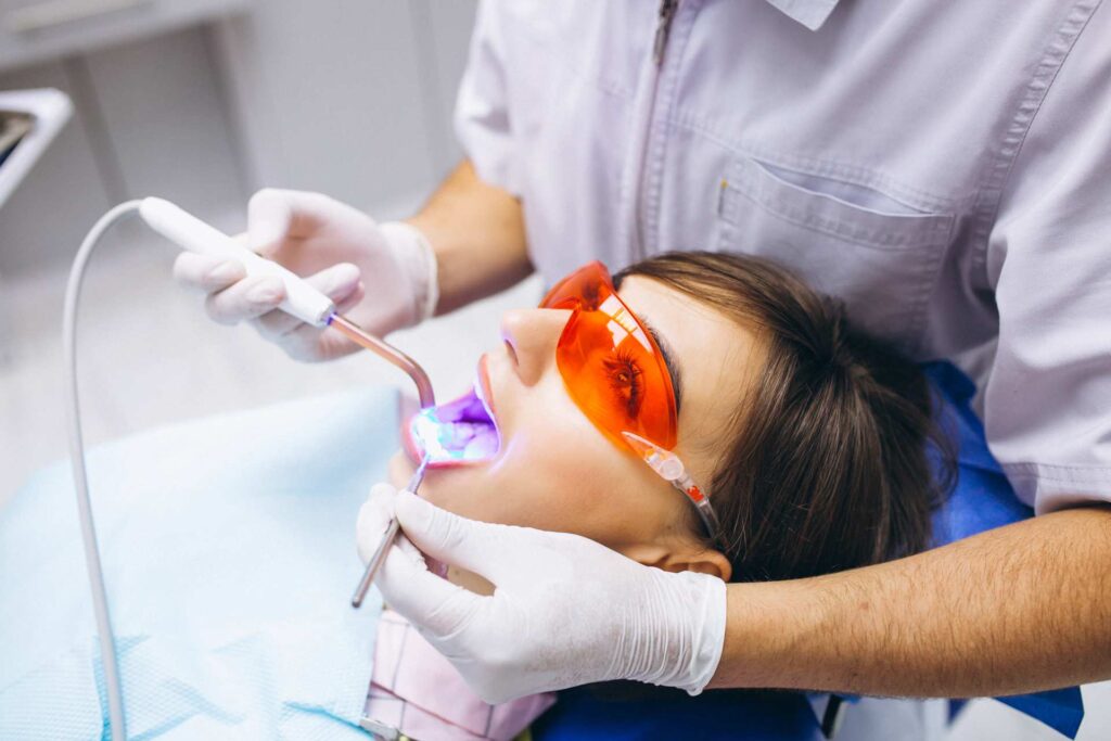 Woman wearing orange goggles during zoom light teeth whitening in a dental clinic